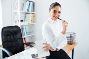 Charming young businesswoman sitting on the table at office