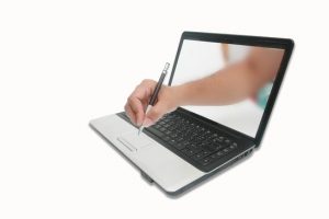 A hand is writing and through the computer screen